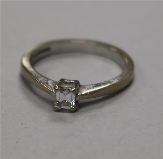 A modern 18ct white gold and solitaire emerald cut diamond ring, size M.